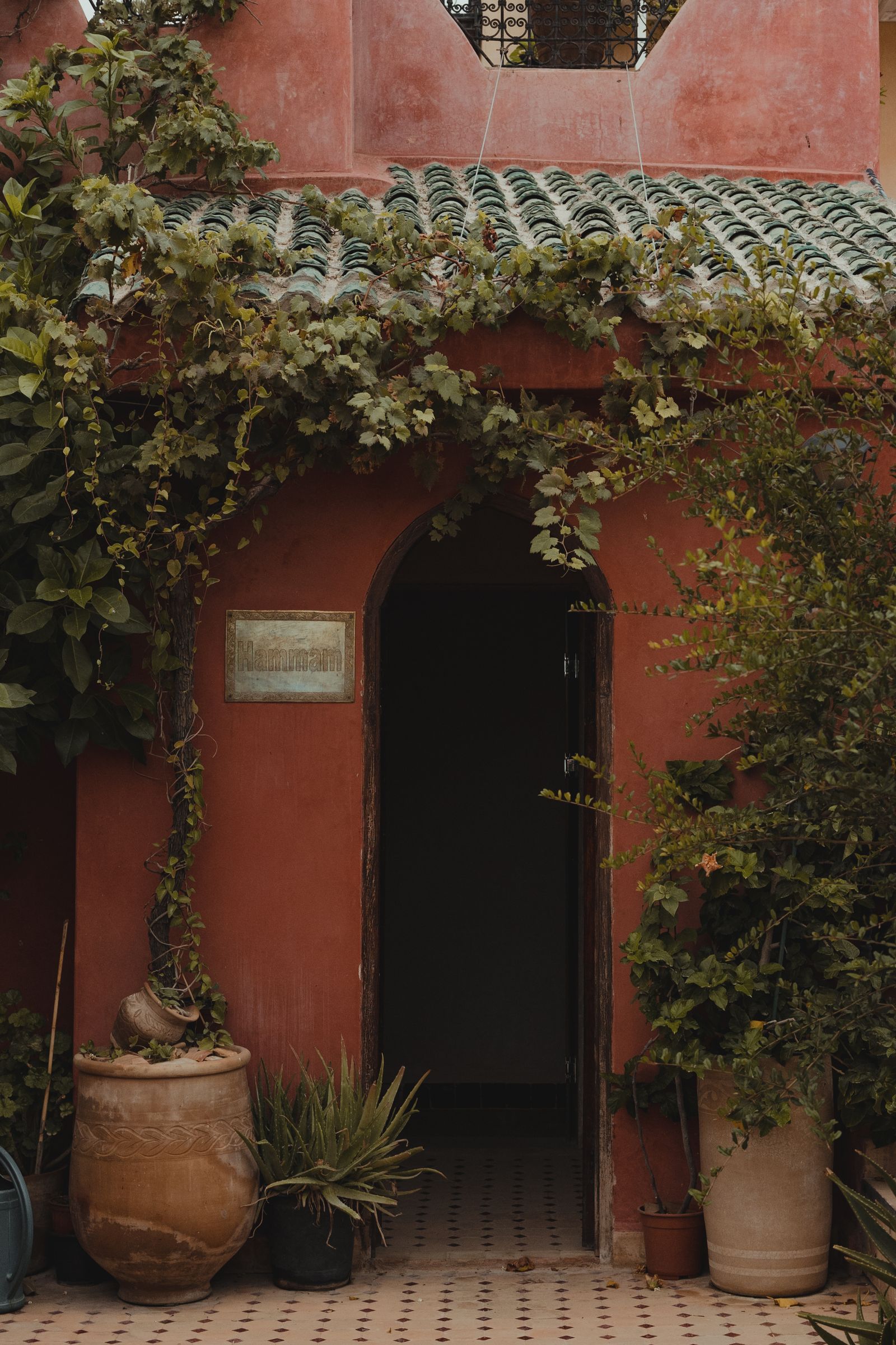Porte traditionnelle marocaine entourée de verdure — l'accueil au pays